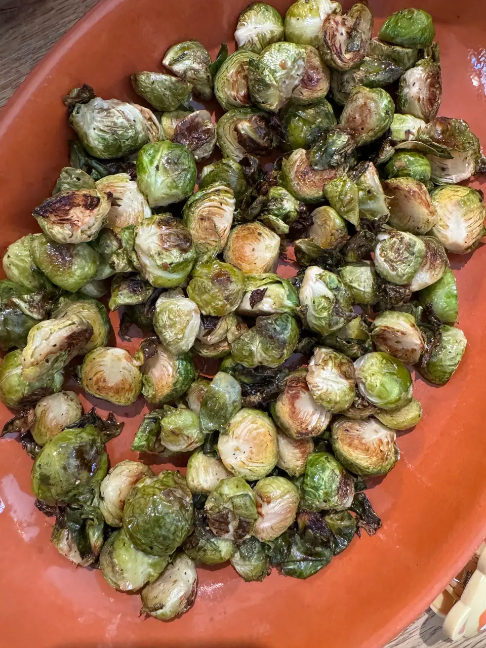 Halved roasted Brussels sprouts with browned edges in a terracotta dish